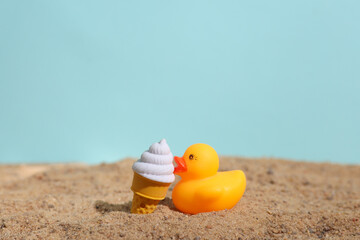 Obraz premium Rubber duck with ice cream on the sand. Beach holiday, summer time