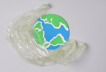 Pollution, eco concept. Globe model with plastic bag on gray background