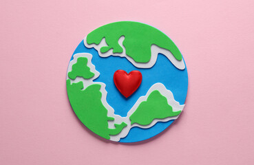 Planet earth with heart on pink background. Love concept