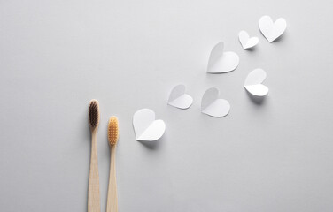 Wooden toothbrushes with hearts on a gray background. Teeth care, love, eco concept