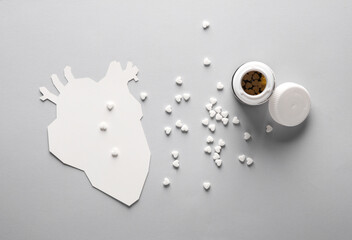 Paper-cut anatomical heart with pills on a gray background. Treatment of heart disease