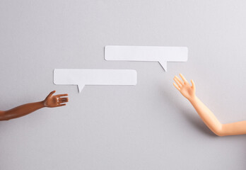 Doll's hands and paper-cut speech bubble on a gray background. Social media, friendship