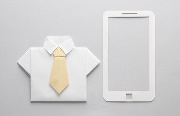 Paper cut smartphone and origami shirt on gray background.