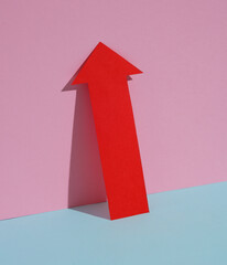 Red up arrow on blue-pink pastel background. Creative layout
