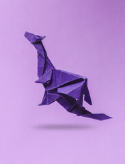 Origami dragon levitating on purple background