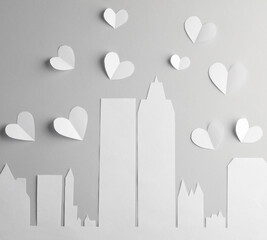 Paper-cut city buildings, skyscrapers and hearts on a gray background. Love concept
