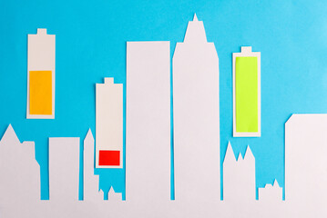 Paper-cut city and batteries with different charge levels on a blue background.