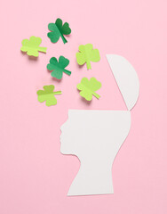 Paper cut Head silhouette with clover leaves on pink background