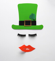 Creative st patrick's day layout with leprechaun hat, eyelashes and lips on white background