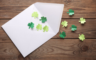 St. patrick's day invitation. Envelope with clover leaves on wooden background. Flat lay