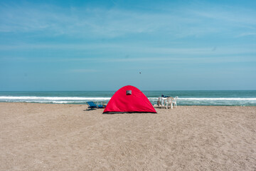 Background photos of a tent on the beach with a blue sky.
