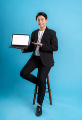 Full body Young business man wearing a vest using laptop and posing on a blue background