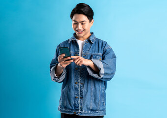 Young asian man using phone on a blue background