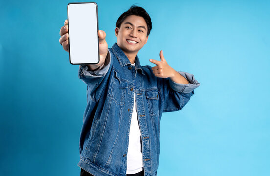 Young Asian Man Using Phone On A Blue Background