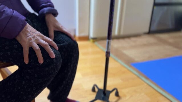 the old man's hand sitting with a cane beside him..
