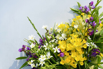 Wildflowers bunch on light gray table. Spring Wild flowers on white or beige background, copy space. Beautiful Floral background