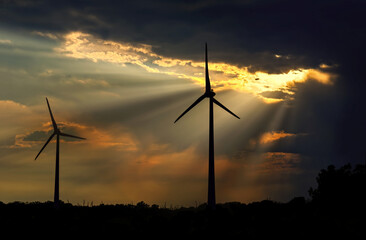 Obraz premium Dark storm clouds over silhouette of two wind turbines in the field, copy space