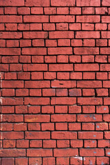 Fototapeta premium Bright red brick wall background. Red brick texture. Old handmade brick. Brick wall with broken bricks. vertical photo