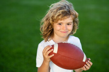 Outdoor kids sport activities. Kid boy having fun and playing american football on green grass park.