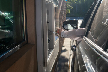 Man's hand from the car with card near ATM. Man using - ATM drive through. Money withdrawal