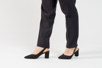 Female legs in strict business black trousers and high-heeled shoes close-up on a white background / Business woman concept