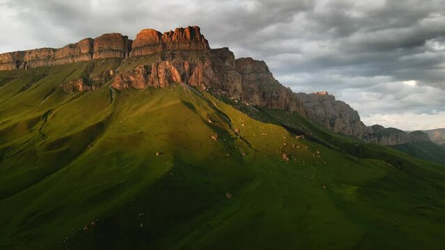 Green mountains in the evening sunlight. Aerial drone view. Summer landscape. Aktoprak pass in North Caucasus, Russia.
