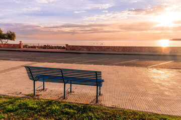 metallic bench on sea embarkment with asphalt road and beautiful seashore landscape with amazing cloudy sky