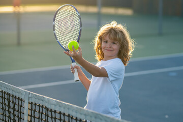 Child playing tennis on outdoor court. Child swinging racket while training on tennis. Tennis child player on tennis court. Sport concept.