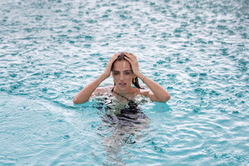 Rain in summer. Beautiful girl relaxing outdoor swimming pool. Enjoying summer vacation. Sexy woman relaxing in swimming pool. Beautiful model enjoying summer travel vacation.