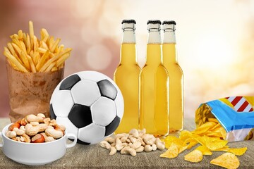 Beer bottles and snack on table with classic football ball,