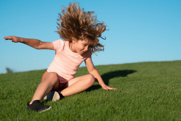 Kid falling down on the grass. Moment of the fall down. Little child tripped and falls down. Fall...