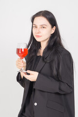 Cute young brunette girl with a glass of wine on a white background. Image of an alcoholic woman