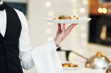 Fine dining, food and waiter serving at a restaurant for a luxury valentines day or anniversary meal. Formal, hospitality service and server with a plate or dish for a fancy special dinner date.