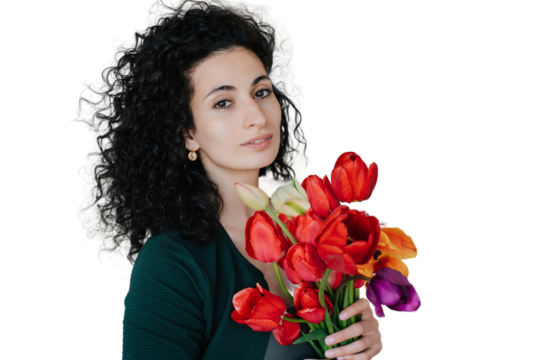 Pretty greatful curly young woman against transparent background holds colourful tulips looks at camera. Remote working hispanic businesswoman received flowers on women day, mother's day. valentine.