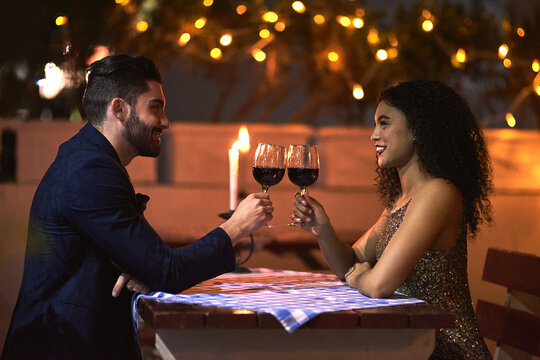 Love, wine and toast of couple on date for fine dining, restaurant or night valentine celebration together. Happy black woman with romance partner alcohol glass, celebrate and luxury in night bokeh
