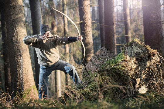 Man shooting with bow and arrow in the forest, Bavaria, Germany