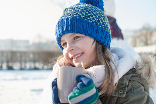 Girl drinking hot tea on snow field