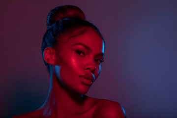Fashion portrait African American Fashion Model posing on Blurred colored abstract background. Satisfied Brunette young woman with bun hairstyle looking at camera ,creative Colorful lighting filter