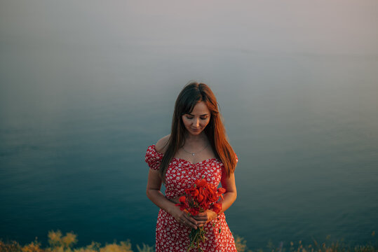 woman with a bouquet of flowers on the background of the sea in summer