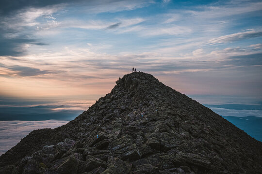 two tiny figures stand on summit of Mount Katahdin, Maine, sunrise