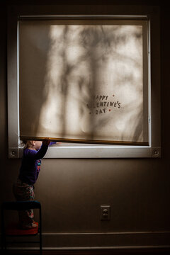 Valentine's Day Image Of Child Peeking Out Of Window In Morning Light