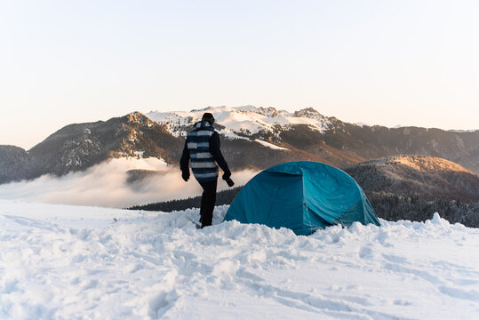 Male Sitting by Tent in Cold Winter Morning
