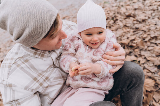 Dad holding his two-year-old daughter outdoors in spring