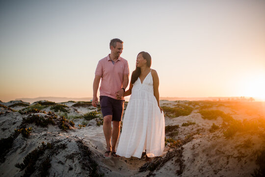 Husband & Pregnant Wife Holding Hands on Beach at Sunset in San Diego