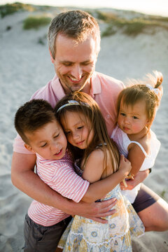 Close Up of Dad Holding His Three Children on Beach in San Diego