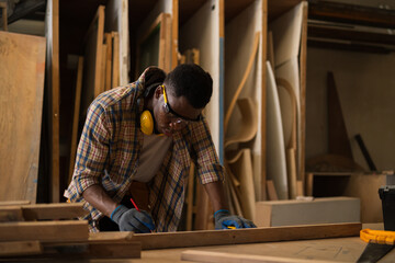 Black African Carpenter professional craftsmen wear safety gear. He was measuring the size and...