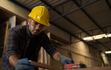 Professional carpenter craftsmen wear safety gear. He was measuring the size and making wooden plank symbols on the table for the craft. in Carpenter and wood craftsmanship concept.