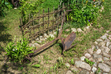 Old rusty plow for plowing the ground lying on the grass