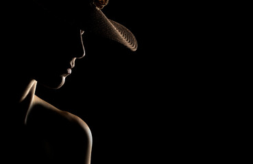 Sensual portrait silhouette of beautiful woman with a hat in backlight on a black background