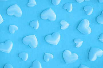 Background from hearts and sparkles. Pink hearts on a blue background top view. Background for love flat lay. The concept of a holiday, miracles and surprises.